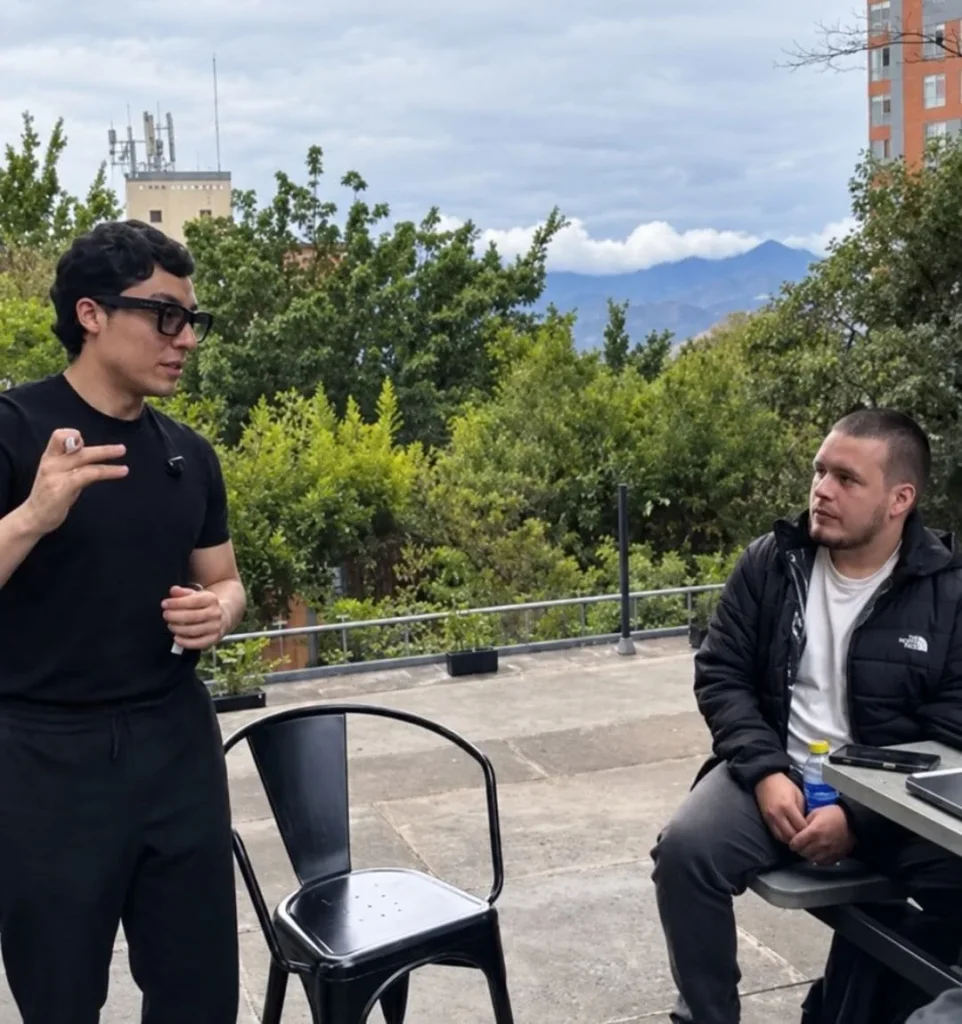 Juan explica de pie, afuera de sus oficinas, mientras yo lo escucho sentado.